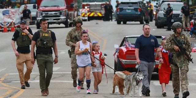 Law enforcement escorts a family away from the scene of a shooting at a Fourth of July parade on July 4, 2022, in Highland Park, Illinois. Police have detained Robert "Bobby" E. Crimo III, 22, in connection with the shooting.
