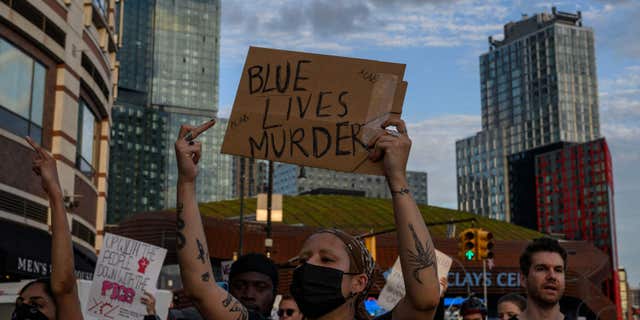 A woman holds a sign reading "Blue Lives Murder" as demonstrators gather outside Barclays Center in New York on July 6, 2022, to protest the killing of Jayland Walker. (Photo by ANGELA WEISS/AFP via Getty Images)