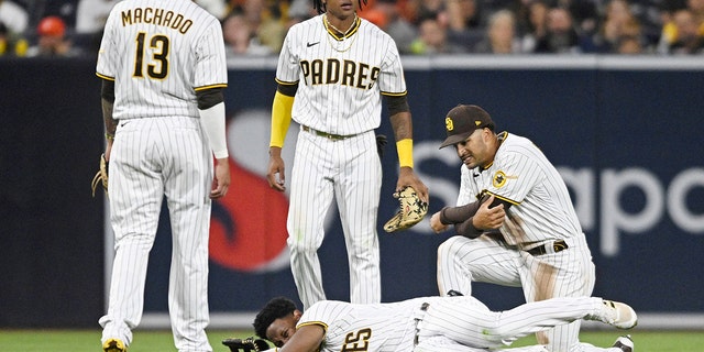 San Diego Padres (c) lie on the ground as No. 10 Jurikson professors, Manny Machado, #13 (l), CJ Abrams, #77, and Trent Grisham, #2, watch during baseball's fifth inning Game against the San Francisco Giants on July 7, 2022 at Petco Park in San Diego, California.  The professor got injured in the play. 