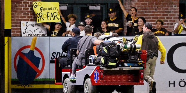 Fans hold up signs as Jurickson Profar, #10 of the San Diego Padres, is taken away in a cart during the fifth inning of a baseball game against the San Francisco Giants July 7, 2022 at Petco Park in San Diego, California. Profar was injured during a collision with C.J. Abrams, #77 of the San Diego Padres.