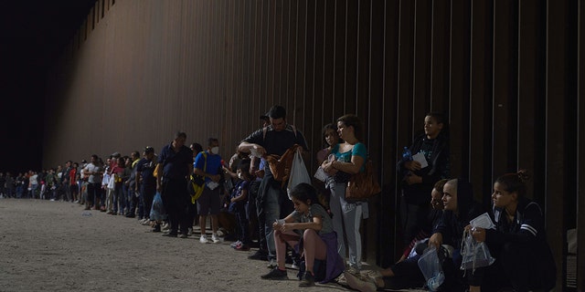 Migrants line up as they wait to be processed by US Border Patrol after illegally crossing the US-Mexico border in Yuma, Arizona in the early morning of July 11, 2022.