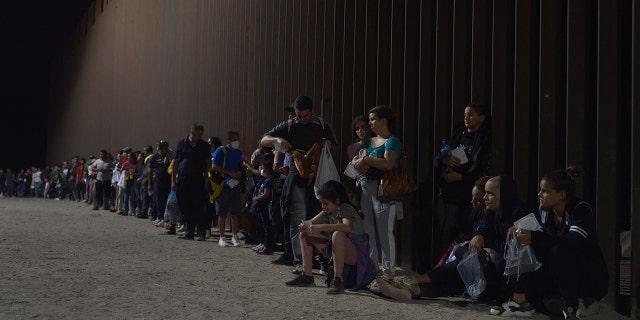 Immigrants await processing by U.S. Border Patrol after crossing the U.S.-Mexico border illegally in Yuma, Arizona.