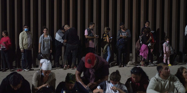 Migrants wait to be processed by the Border Patrol after illegally crossing the US-Mexico border in Yuma, Arizona, in the early morning of July 11, 2022.