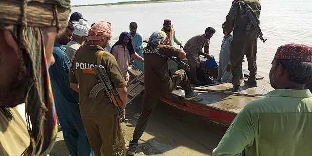 Policemen and local villagers prepare to search for the victims drowned at Indus River after an overcrowded boat carrying a Pakistan wedding party capsized on the outskirt of Sadiqabad town on July 18, 2022.