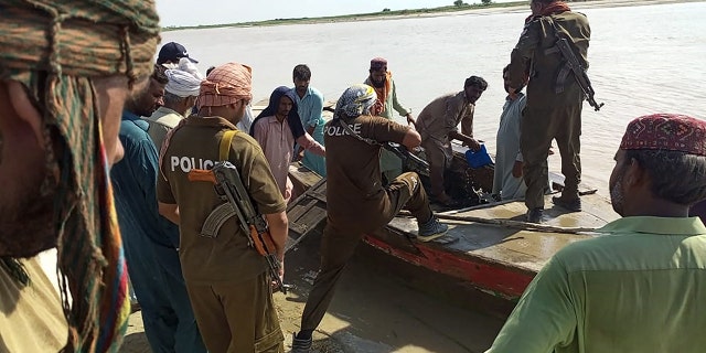 Policemen and local villagers prepare to search for the victims drowned at Indus River after an overcrowded boat carrying a Pakistan wedding party capsized on the outskirt of Sadiqabad town on July 18, 2022.