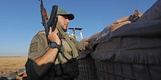 A Turkey-backed fighter looks out from a military position in the Syrian area of Jibrin in Aleppo's eastern countryside, towards the Kurdish-controlled area of Tal Rifaat, on July 19, 2022. 