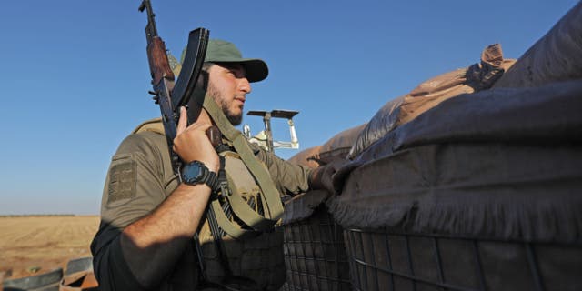 A Turkey-backed fighter looks out from a military position in the Syrian area of Jibrin in Aleppo's eastern countryside, towards the Kurdish-controlled area of Tal Rifaat, on July 19, 2022.