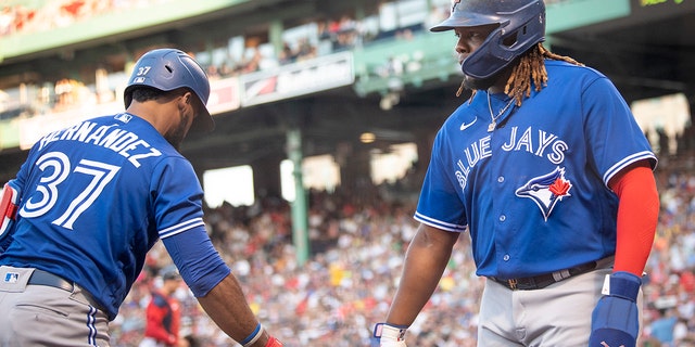 Vladimir Guerrero Jr.  Toronto Blue Jays No. 27 reacts to Toronto Blue Jays No. 37 Theoscar Hernandez after he scored in the first inning against the Boston Red Sox on July 22, 2022 at Fenway Park in Boston, Massachusetts . 