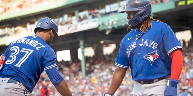 Vladimir Guerrero Jr. #27 of the Toronto Blue Jays reacts with Teoscar Hernández #37 of the Toronto Blue Jays after scoring during the first inning game against the Boston Red Sox on July 22, 2022 at Fenway Park in Boston, Massachusetts. 