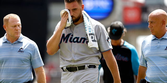 Daniel Castano of the Miami Marlins (center) walks off the field after being hit with a lineman to the head during the first half against the Cincinnati Reds at Great American Ball Park on July 28, 2022 in Cincinnati, Ohio.
