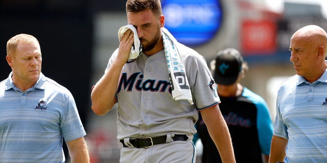 Daniel Castano of the Miami Marlins, center, walks off the field after being hit by a line drive in the head during the first inning against the Cincinnati Reds at Great American Ball Park, July 28, 2022, in Cincinnati, Ohio.