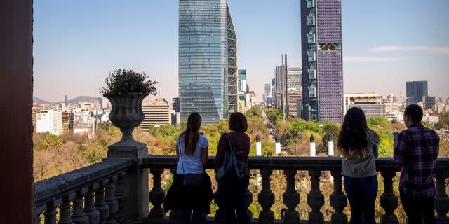 People in foreground at Chapultepec Castle, and Paseo de la Reforma in distance, in Mexico City.