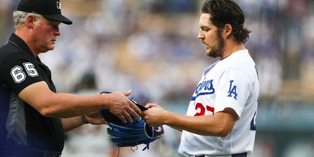 Umpire Ted Barrett #65 checks the hat and glove of Trevor Bauer #27 of the Los Angeles Dodgers for foreign substances after the first inning against the San Francisco Giants at Dodger Stadium on June 28, 2021 in Los Angeles, California.
