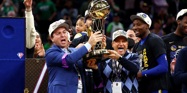 Owners Joe Lacob and Peter Guber of the Golden State Warriors raise the Larry O'Brien Championship Trophy after defeating the Boston Celtics 103-90 在第六场比赛中 2022 6 月在 TD Garden 举行的 NBA 总决赛 16, 2022 在波士顿, 马萨诸塞州.