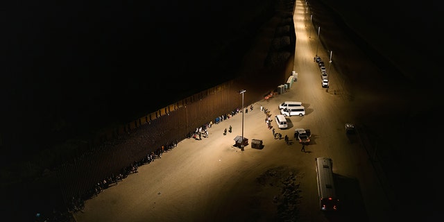 YUMA, ARIZONA - JUNE 22: Aerial view of immigrants waiting to be processed by the U.S. Border Patrol after crossing the border from Mexico, with the U.S.-Mexico border barrier in the background, in the early morning hours on June 22, 2022 in Yuma, Arizona. (Photo by Qian Weizhong/VCG via Getty Images)