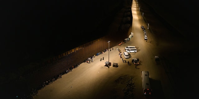 YUMA, ARIZONA - JUNE 22: Aerial view of immigrants waiting to be processed by the U.S. Border Patrol after crossing the border from Mexico, with the U.S.-Mexico border barrier in the background, in the early morning hours on June 22, 2022 in Yuma, Arizona. (Photo by Qian Weizhong/VCG via Getty Images)