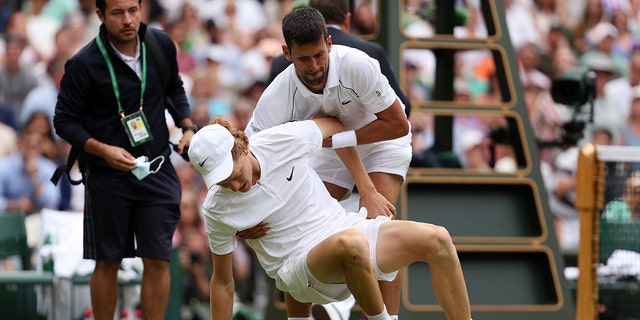 Novak Djokovic de Serbie aide Jannik Sinner d'Italie après avoir glissé et chuté lors de leur match de quart de finale du simple masculin le neuvième jour des Championnats de Wimbledon 2022 au All England Lawn Tennis and Croquet Club le 05 juillet 2022 à Londres, en Angleterre. 