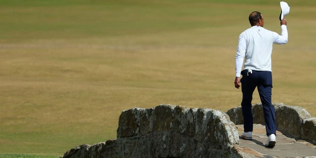 Tiger Woods of the United States acknowledges the crowd as he crosses the Swilcan Bridge during Day Two of The 150th Open at St Andrews Old Course on July 15, 2022 in St Andrews, Scotland. 