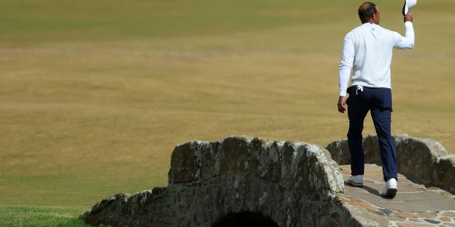 Tiger Woods of the United States acknowledges the crowd as he crosses the Swilcan Bridge during Day Two of The 150th Open at St Andrews Old Course on July 15, 2022 in St Andrews, Scotland.