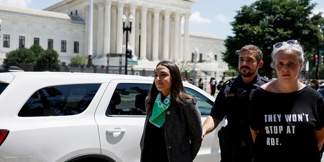 Rep. Alexandria Ocasio-Cortez, D-N.Y., is escorted by U.S. Capitol Police officers after participating in a sit in with activists from Center for Popular Democracy Action (CPDA) in front of the U.S. Supreme Court Building on July 19, 2022.