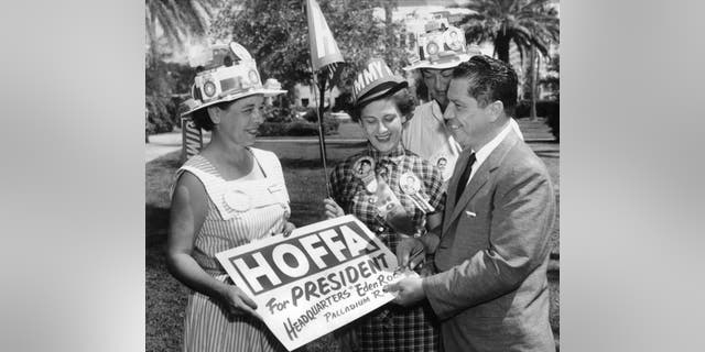 Teamsters union vice president Jimmy Hoffa autographs a placard for him for a group of women campaigning for his run for president of the Teamsters, Miami Beach, Florida, October 1, 1957.