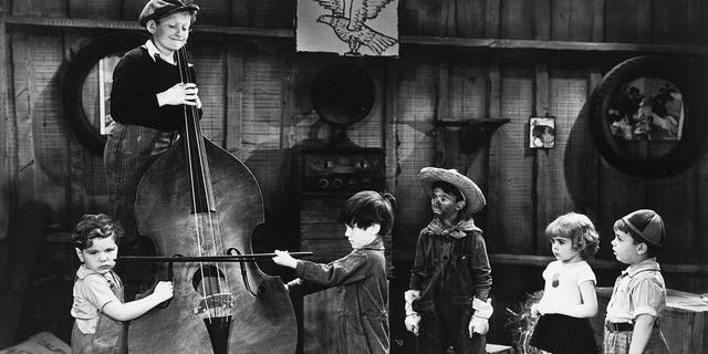 Sidney Kibrick (wearing a hat) is seen here having fun on set with a cello. From left: Tommy Bond (1926-2005), Kibrick, Scotty Beckett (1929-1968), Carl Switzer (1927-1959), Darla Hood (1931-1979) and George McFarland (1928-1993). Photo circa 1935.