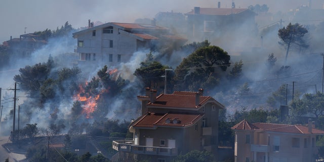 El fuego arde junto a las casas en el área de Drafi al este de Atenas el miércoles 20 de julio de 2022. Cientos de personas fueron evacuadas de sus hogares el martes por la noche cuando un incendio forestal amenazó los suburbios de las montañas al noreste de Atenas.  Los bomberos lucharon durante la noche, luchando por contener el fuego que se estaba intensificando por fuertes ráfagas de viento.  (Foto AP/Thanassis Stavrakis)