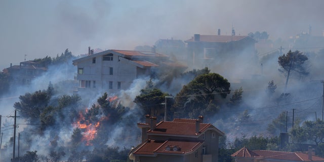 Fire burns next to houses in the area of Drafi east of Athens on Wednesday, July 20, 2022. Hundreds of people were evacuated from their homes late Tuesday as a wildfire threatened mountainside suburbs northeast of Athens. Firefighters battled through the night, struggling to contain the blaze which was being intensified by strong gusts of wind. (AP Photo/Thanassis Stavrakis)