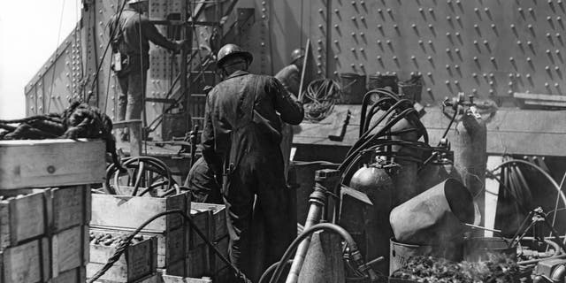 The Golden Gate Bridge is shown while under construction, with workmen putting the finishing touches on the South Tower in San Francisco in 1935. The Golden Gate Bridge was the first major construction project in America that required workers to wear hard hats.