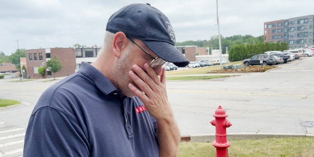 A witness to the Highland Park attack wipes away tears as he recounts the shooting.