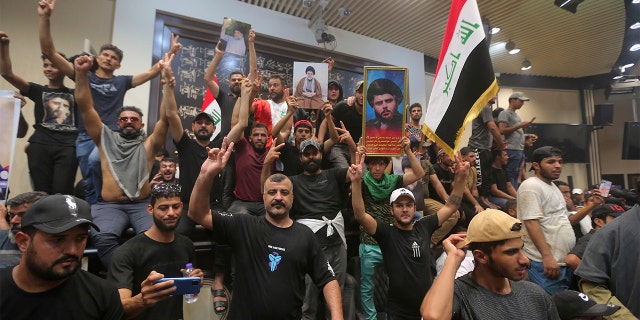 Iraqi protesters pose with national flags and pictures of Shiite cleric Muqtada al-Sadr inside the parliament building in Baghdad, Iraq, Saturday, July 30, 2022.
