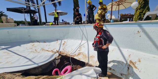 A first responder stands next to the damage caused by a sinkhole, which opened during a pool party in central Israel; one man died and another was injured on Thursday 21 July 2022.