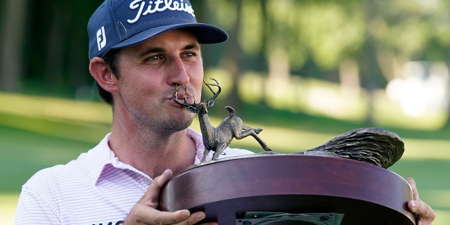 J.T. Poston kisses the trophy after winning the John Deere Classic golf tournament, Sunday, July 3, 2022, at TPC Deere Run in Silvis, Ill. 