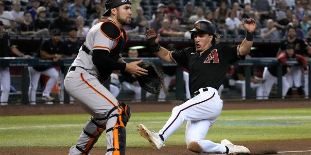 Arizona Diamondbacks' Jake McCarthy, right, scores on an error by San Francisco Giants first baseman Brandon Belt during the seventh inning of a baseball game Wednesday, July 27, 2022, in Phoenix.