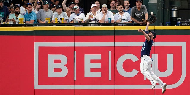 Seattle Mariners left fielder Jesse Winker makes a leaping catch of a fly ball hit by Texas Rangers' Corey Seager during the sixth inning of a baseball game, Tuesday, July 26, 2022, in Seattle.