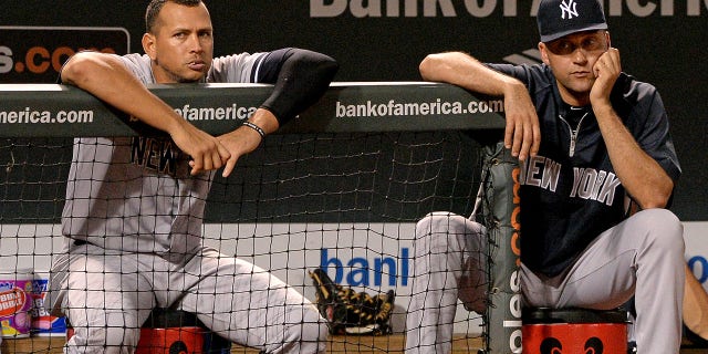 Alex Rodriguez #13 (L) and Derek Jeter #2 of the New York Yankees look on against the Baltimore Orioles in the ninth inning at Oriole Park at Camden Yards on September 11, 2013 in Baltimore, Maryland.