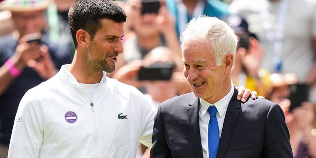 Novak Djokovic greets John McEnroe during the Centre Court Centenary Celebration during Wimbledon on July 3, 2022, in London.