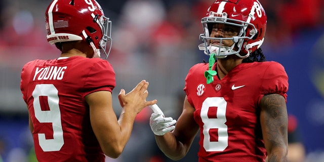 Bryce Young (9) of the Alabama Crimson Tide talks with teammate John Metchie III (8) before the SEC Championship game against the Georgia Bulldogs at Mercedes-Benz Stadium Dec. 4, 2021, in Atlanta.