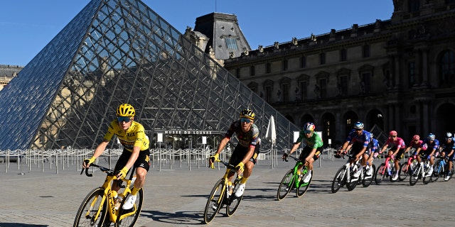 The pack with Denmark's Jonas Vingegaard, wearing the overall leader's yellow jersey, passes the Louvre Museum during the twenty-first stage of the Tour de France cycling race over 116 kilometers (72 miles) with start in Paris la Defense Arena and finish on the Champs Elysees in Paris, France, Sunday, July 24, 2022.