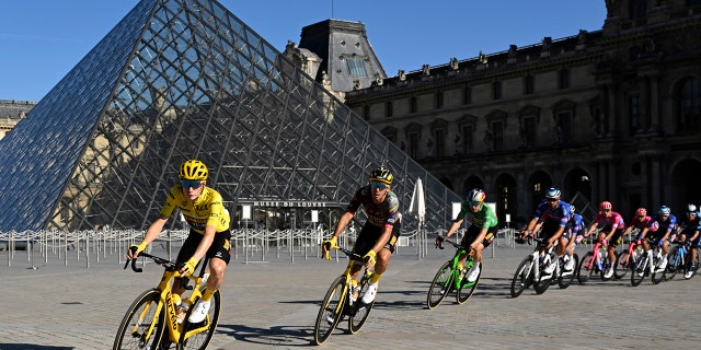 The pack with Denmark's Jonas Vingegaard, wearing the overall leader's yellow jersey, passes the Louvre Museum during the twenty-first stage of the Tour de France cycling race over 116 kilometers (72 miles) with start in Paris la Defense Arena and finish on the Champs Elysees in Paris, France, Sunday, July 24, 2022. 