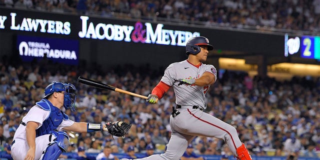 Washington Nationals' Juan Soto, right, hits a two RBI triple as Los Angeles Dodgers catcher Will Smith watches during the fifth inning of a baseball game Monday, July 25, 2022, in Los Angeles. 