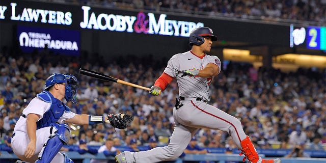 Washington Nationals' Juan Soto, right, hits a two RBI triple as Los Angeles Dodgers catcher Will Smith watches during the fifth inning of a baseball game Monday, July 25, 2022, in Los Angeles.