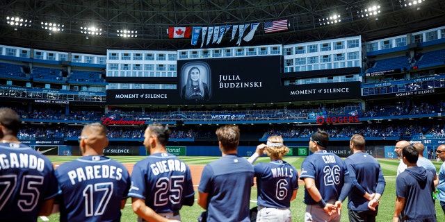 Tampa Bay Rays players and staff stand for a moment of silence on the death of Julia Budzinski, the eldest daughter of Blue Jays first base coach Mark Budzinski, at Rogers Centre on July 3, 2022, in Toronto, Canada.