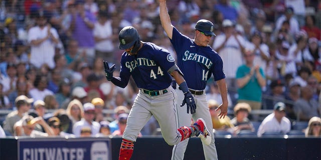 Seattle Mariners' Julio Rodriguez, left, reacts with third base coach Manny Acta after hitting a two-run home run during the fourth inning of a baseball game against the San Diego Padres, Monday, July 4, 2022, in San Diego. 