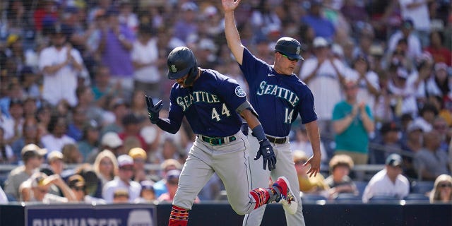 Seattle Mariners' Julio Rodriguez, left, reacts with third base coach Manny Acta after hitting a two-run home run during the fourth inning of a baseball game against the San Diego Padres, Monday, July 4, 2022, in San Diego.