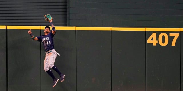 Seattle Mariners center fielder Julio Rodriguez (44) jumps to catch a fly out at the wall against Texas Rangers Adolis Garcia during the second inning of a baseball game in Arlington, Texas, Sunday, July 17, 2022.