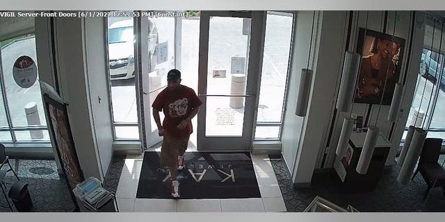 The suspect reaching into his cargo shorts to grab his brick as he was walking into the jewelry store.