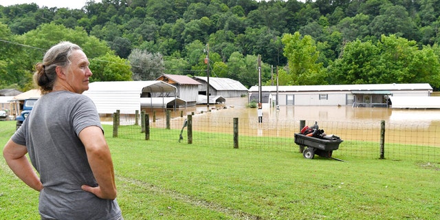 Bonnie Combs stands by and watches her property become covered by the North Fork of the Kentucky River in Jackson, Ky., Thursday, July 28, 2022.