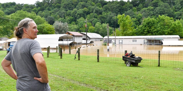 Bonnie Combs stands by and watches as her property is covered on the North Fork of the Kentucky River in Jackson, Kentucky, Thursday, July 28, 2022.