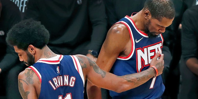 The Nets' Kyrie Irving pats teammate Kevin Durant during a Celtics game.